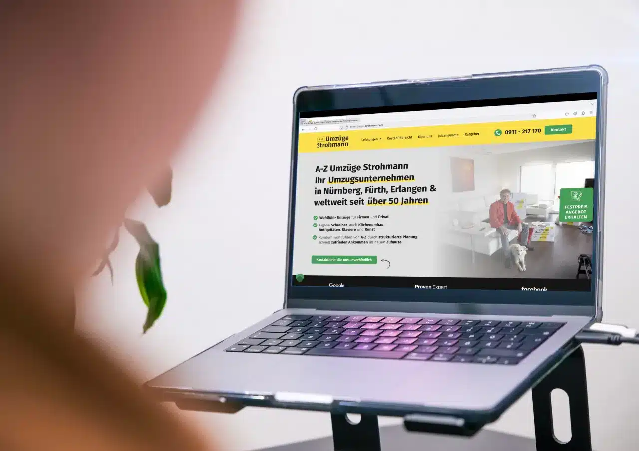 Eine Person betrachtet auf ihrem Laptop die Kundenwebsite eines Umzugsunternehmens aus Nürnberg, Fürth und Erlangen mit über 50 Jahren Erfahrung. Auf dem Bildschirm erscheint eine kleine, verschwommene Strohmann-Figur.